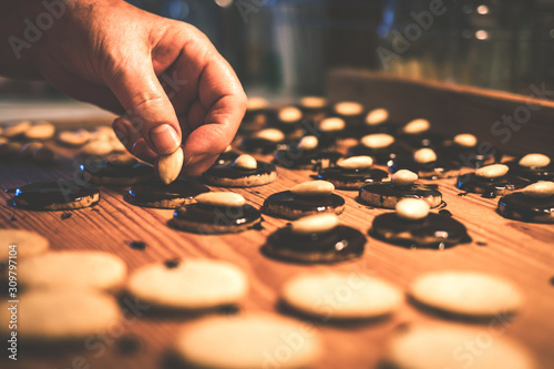 Senior woman decorating homemade chocolate biscuit by almond. Toned image