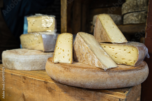 Cantal or saint nectaire french mature morbier cheese on the wooden shelf stored for sale or use organic food market photo