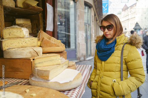Portrait of caucasian woman female tasting and buying organic french cheese on the street market sail saint nectaire or brie in winter or autumn day in europe or america photo