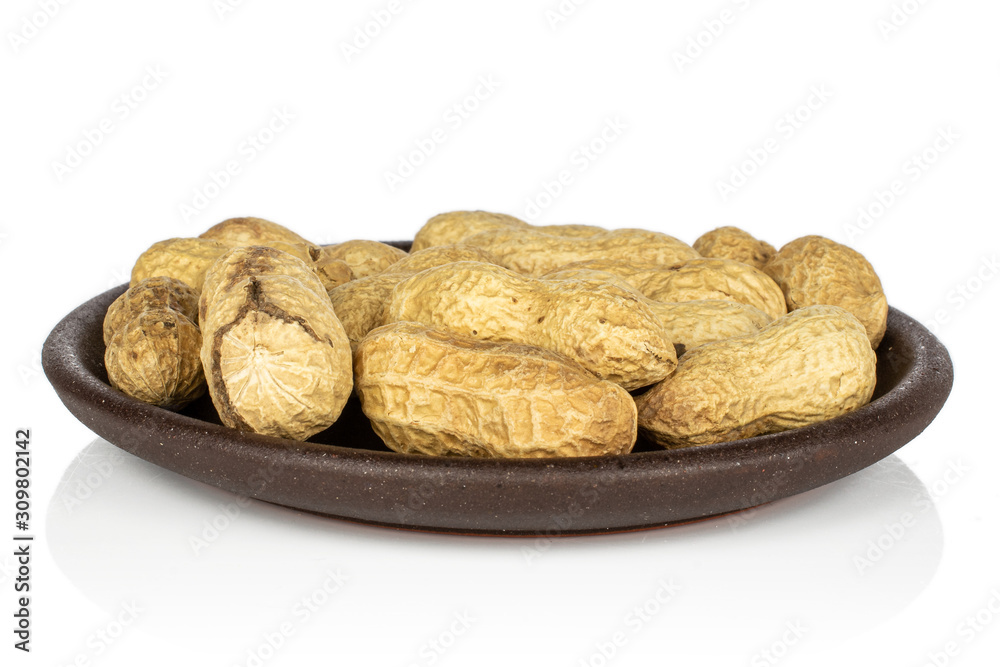 Lot of whole tasty beige peanut with brown ceramic coaster isolated on white background Lot of whole tasty beige peanut with brown ceramic coaster isolated on white background