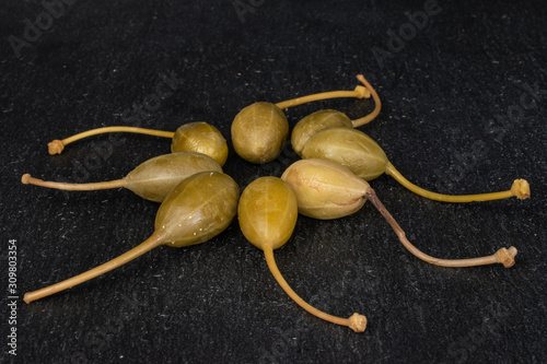 Group of eight whole pickled green caper on grey stone