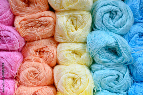 background of rows skeins of thin fluffy wool yarn for knitting different pastel colors. soft light color of pink, orange, yellow, mint and blue