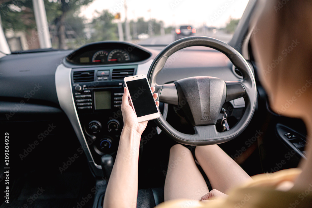 Young woman in car checking her smartphone while driving Young woman in car checking her smartphone while driving