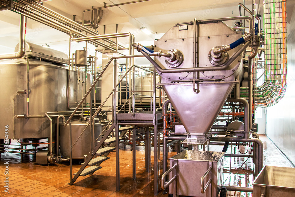 The fresh sour milk cheese is poured into the container from the grinder at the dairy plant.