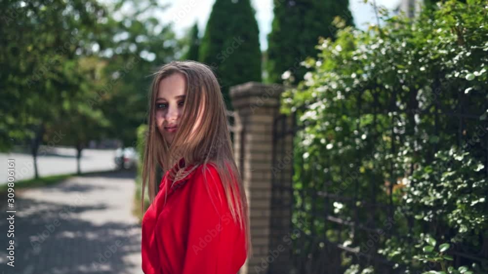 Passionate young girl posing to camera. Beautiful young model in red dress with long hair on the green trees background. Sexy woman turning around herself joyfully. Passionate young girl posing to camera. Beautiful young model in red dress with long hair on the green trees background. Sexy woman turning around herself joyfully.