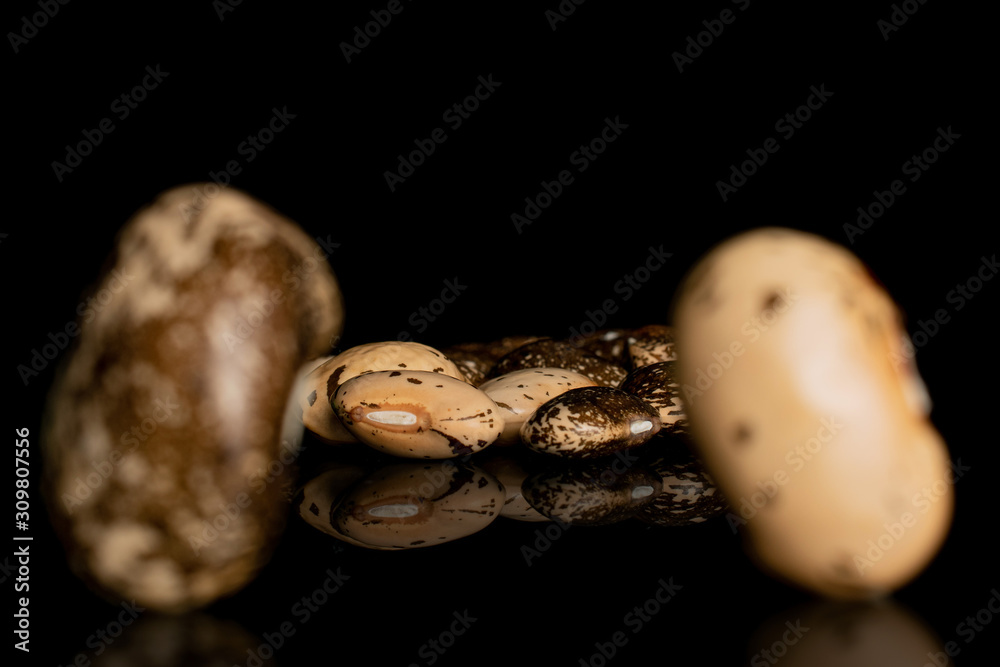 Lot of whole speckled brown bean pinto back focus isolated on black glass Lot of whole speckled brown bean pinto back focus isolated on black glass