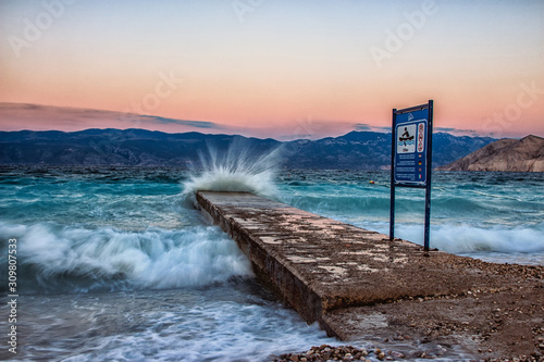Wave hitting pier at sunset 