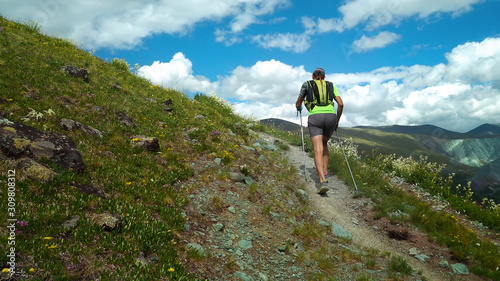 Trail runner climbing a stone trail to the mountain top. Ultra trail running, sport activities, mountain trails marathon.