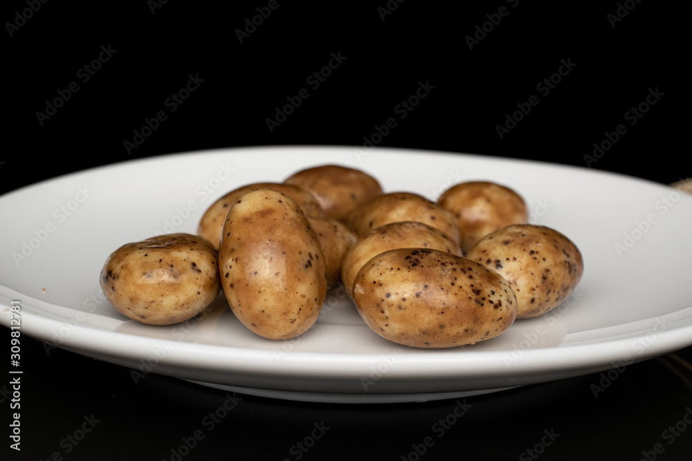 Lot of whole tiramisu brown almond nut on white ceramic plate isolated on black glass Lot of whole tiramisu brown almond nut on white ceramic plate isolated on black glass