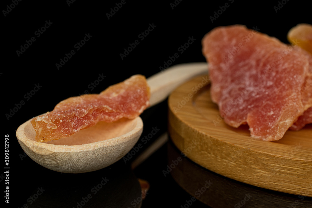 Group of three whole dried orange papaya piece with wooden scoop on round bamboo coaster isolated on black glass Group of three whole dried orange papaya piece with wooden scoop on round bamboo coaster isolated on black glass