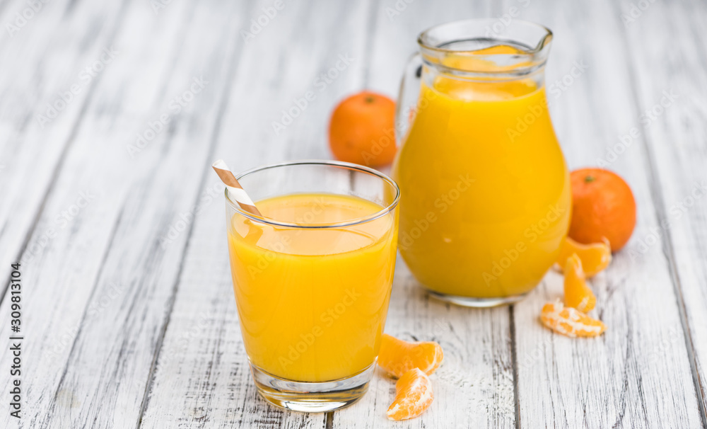 Wooden table with fresh made Tangerine Juice (close-up shot)