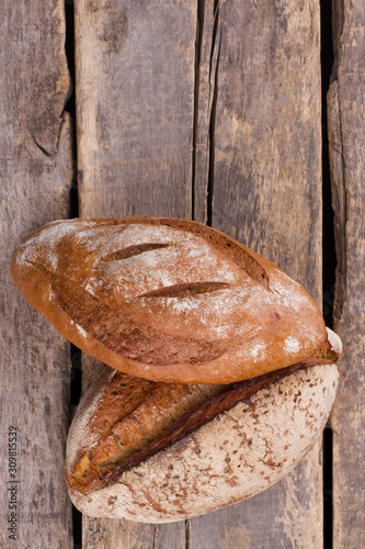 Fresh bread on cracked wooden boards. Whole wheat bread on rustic wooden background, top view.