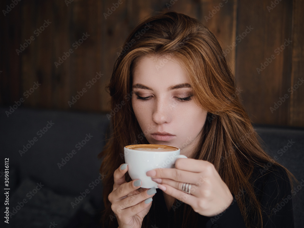 Close up headshot beautiful caucasian red haired woman holding mug drinking cappuccino coffee with latte art adorable smile and feeling good in trendy city cafe Close up headshot beautiful caucasian red haired woman holding mug drinking cappuccino coffee with latte art adorable smile and feeling good in trendy city cafe