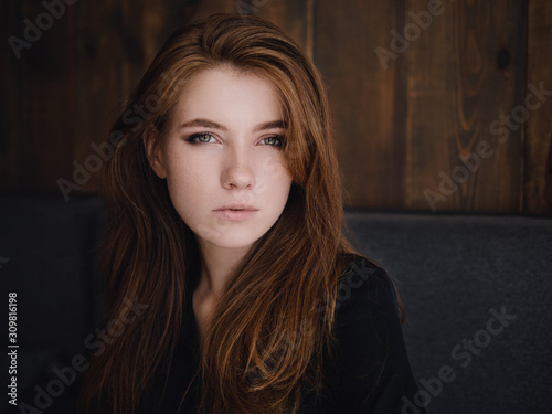 Close up headshot beautiful caucasian red haired woman staring at camera and feeling good in trendy city cafe photo