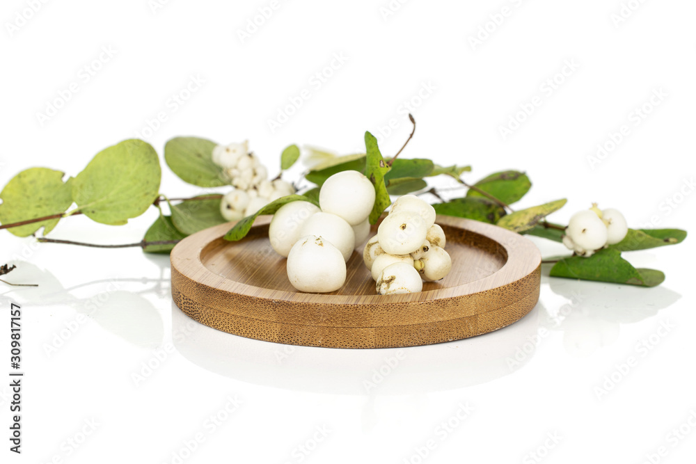 Lot of whole bright white snowberry on round bamboo coaster isolated on white background