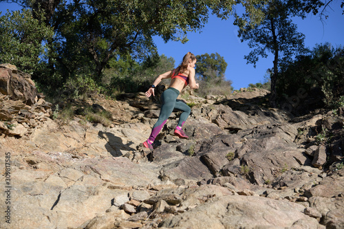 Sportswoman runs up a rock-filled mountain trail while doing her daily workout