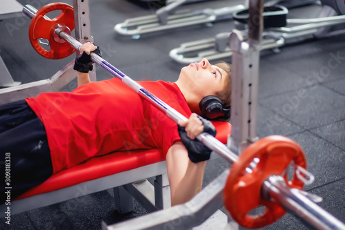 teen doing the bench press bar in the gym