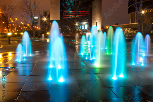 Fountains illuminated at night with colored lights.