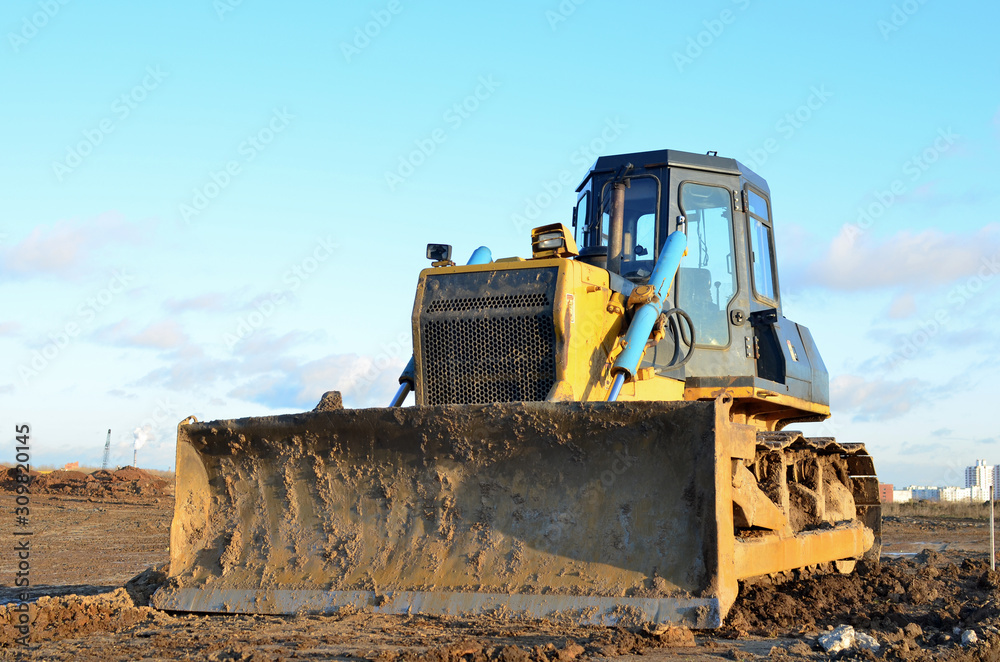 Bulldozer during of large construction jobs at building site. Land clearing, grading, pool excavation, utility trenching and foundation digging. Crawler tractor, dozer, earth-moving equipment. Bulldozer during of large construction jobs at building site. Land clearing, grading, pool excavation, utility trenching and foundation digging. Crawler tractor, dozer, earth-moving equipment.