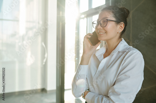 Pretty young smiling businesswoman talking by mobile phone in airport
