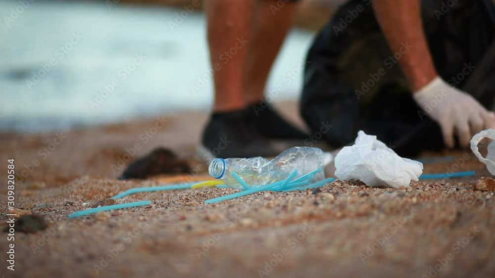 man collecting garbage on a beach, next to the water, concept action to clean the natural environment man collecting garbage on a beach, next to the water, concept action to clean the natural environment