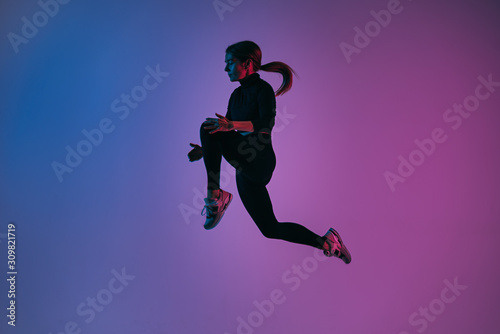 Handsome woman with perfect body jumping against colorful trendy background. Young athletic girl in jump moment in studio