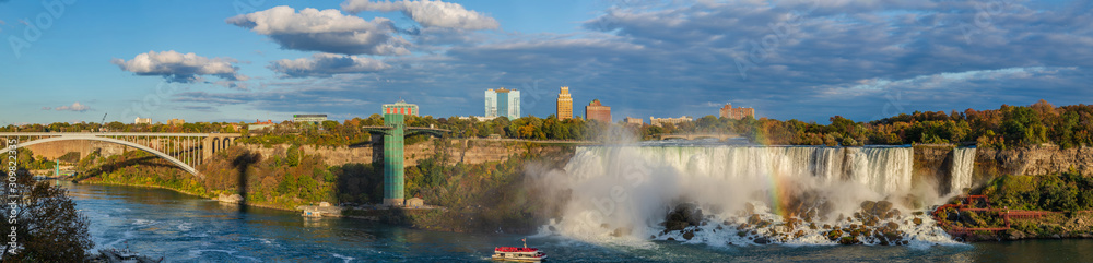 Naklejka premium Niagara Falls - American Falls and Bridal Veil Falls with a rainbow in the sunset rays of the setting sun. View from Canadian Side