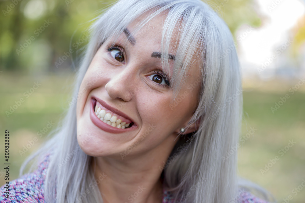 Fototapeta premium Outdoors portrait of a woman making funny faces. Silver hair.