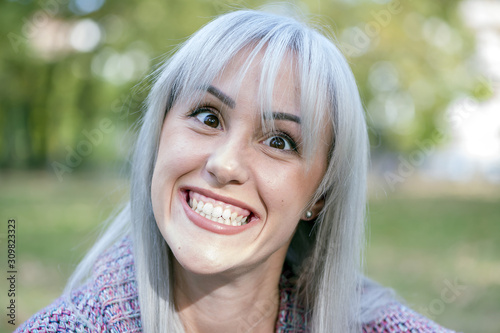 Outdoors portrait of a woman making funny faces. Silver hair.