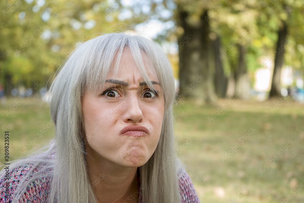 Outdoors portrait of a woman making funny faces. Silver hair.