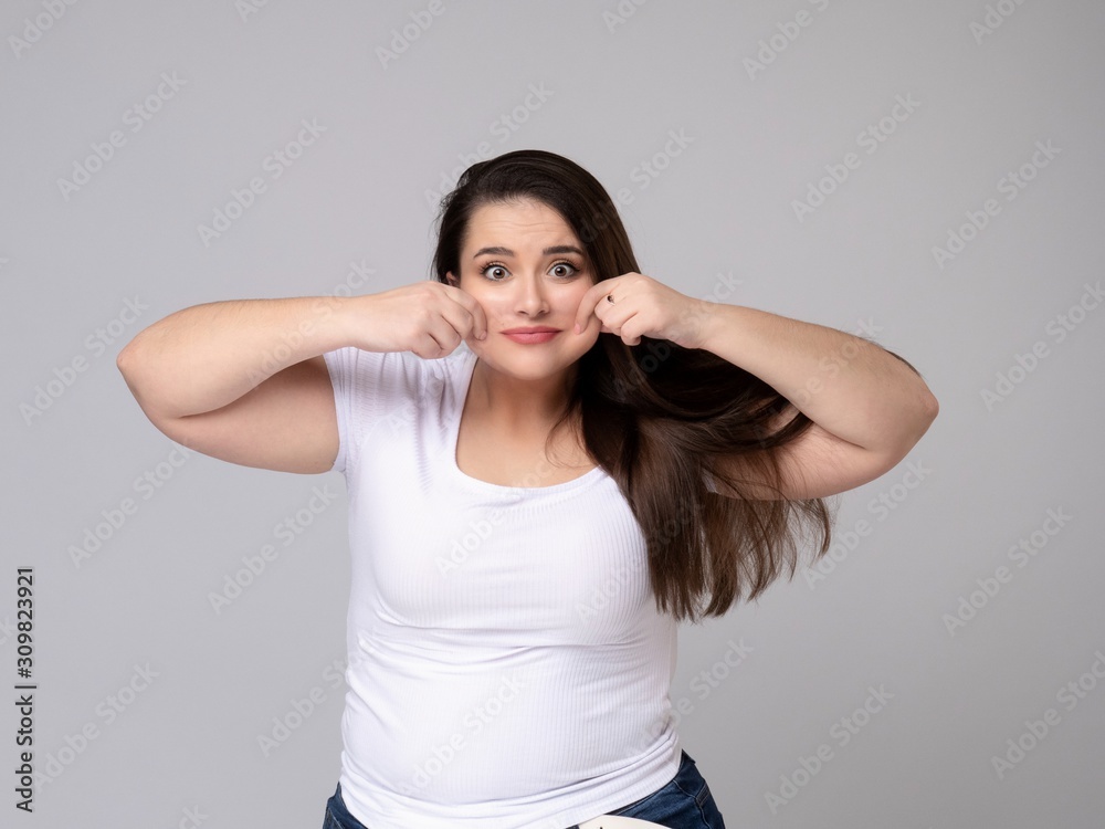 Plus Size Model with long hair Grimacing, pulling her cheeks. Plus Size Model with long hair Grimacing, pulling her cheeks.