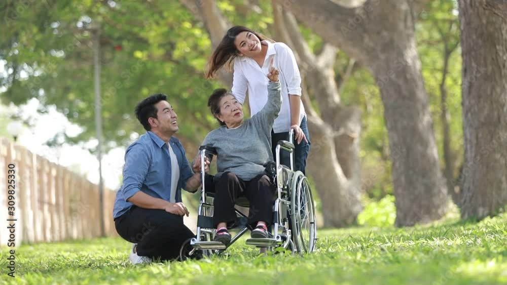 Asian woman sitting on wheelchair in the park with family Asian woman sitting on wheelchair in the park with family