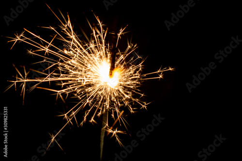 Sparkling sparkler on a black background. New Year theme..