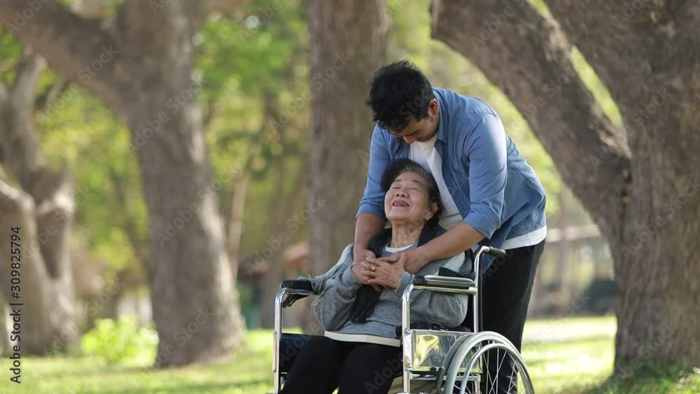 Asian woman sitting on wheelchair in the park with family Asian woman sitting on wheelchair in the park with family