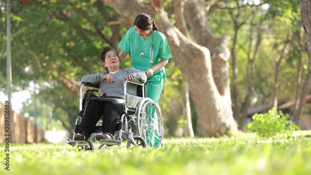 Asian woman sitting on wheelchair in the park with family Asian woman sitting on wheelchair in the park with family