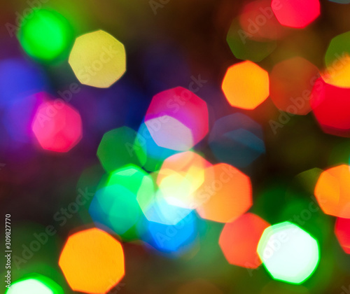 Glowing and festive colored light circles created from in camera and lens bokeh. Christmas fairy lights defocused giving a blurred effect. Background for design.