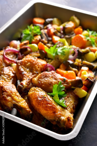 Baked chicken wings with vegetables in baking tray