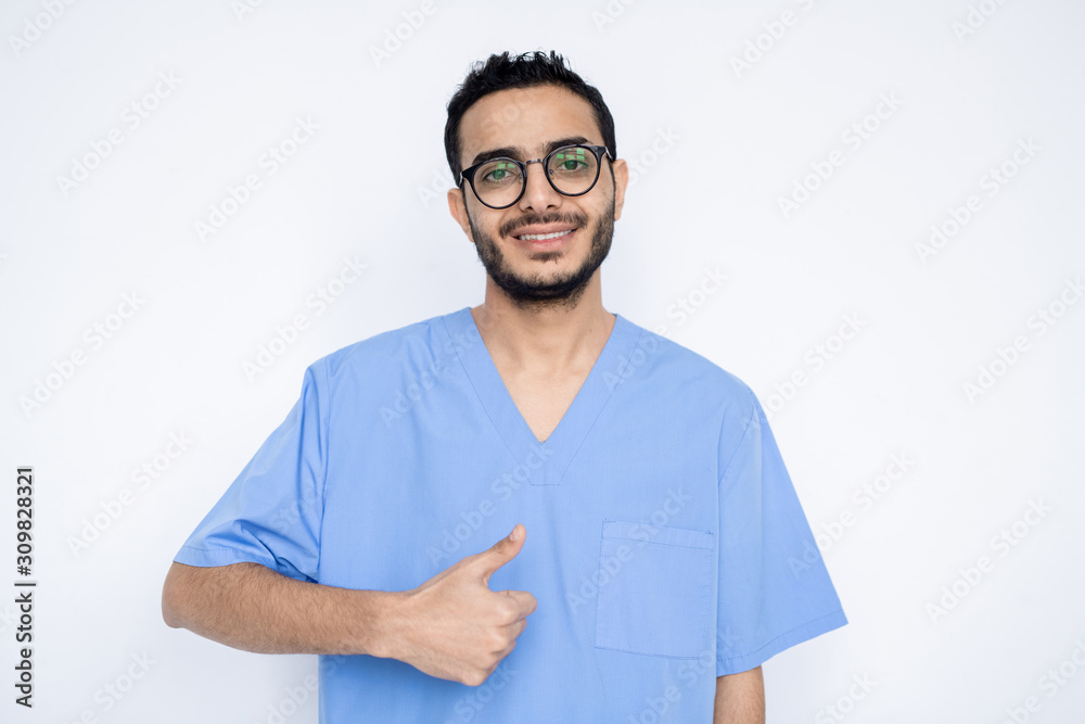 Young successful male surgeon or clinician in blue uniform showing thumb up Young successful male surgeon or clinician in blue uniform showing thumb up