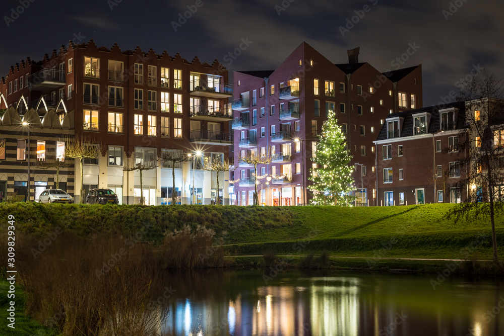 Scenic night view of buildings and christmas tree along a waterside. Centre of the town of Waddinxveen, Netherlands.