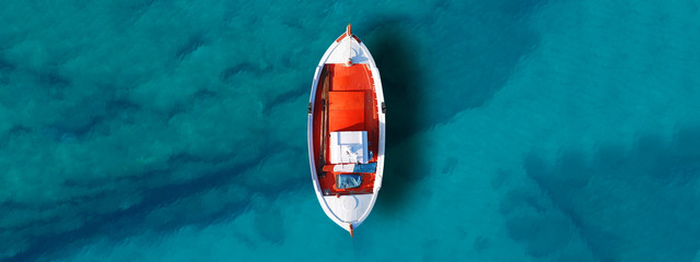 Aerial drone top down ultra wide photo of traditional fishing boat docked in world famous paradise beach of Mykonos island, Cyclades, Greece