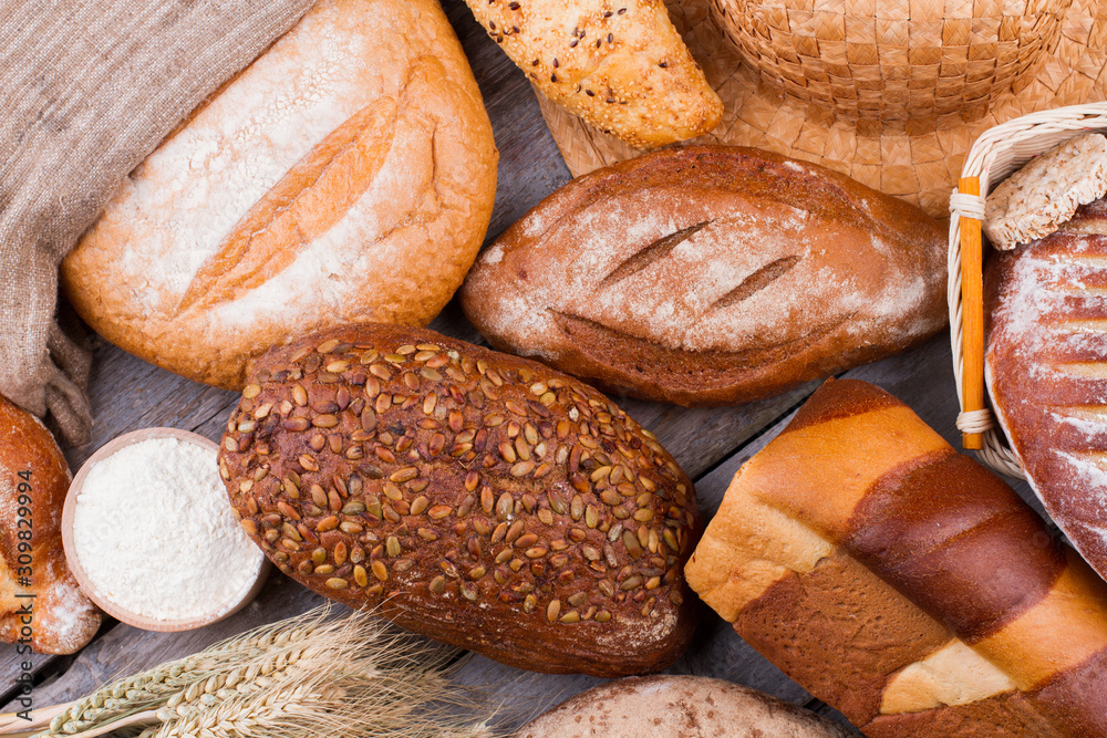Rustic bread background. Assortment of baked wheat bread on wooden background.