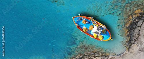 Aerial drone top down ultra wide photo of traditional fishing boat docked in world famous paradise beach of Mykonos island, Cyclades, Greece © aerial-drone