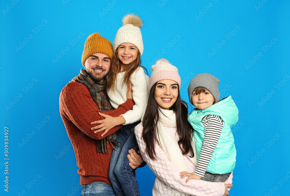 Happy family in warm clothes on blue background. Winter vacation