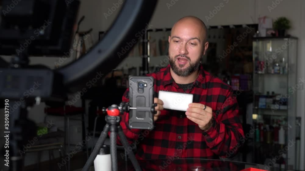 Young blogger recording advertise video at workspace. Handsome guy convincing to buy product. Concentrated vlogger streaming video at coworking space. Young blogger recording advertise video at workspace. Handsome guy convincing to buy product. Concentrated vlogger streaming video at coworking space.