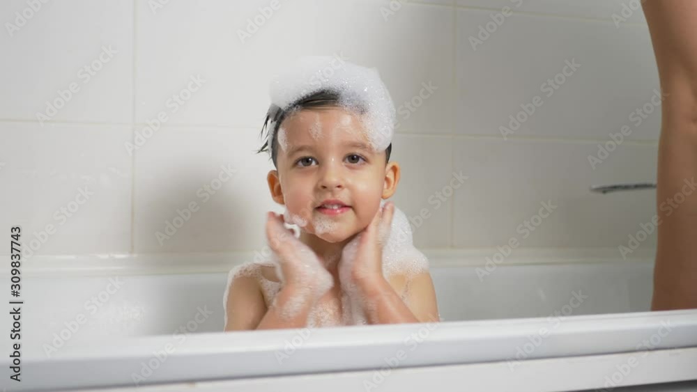 baby boy bathes in a bubble bath and mom baby boy bathes in a bubble bath and mom