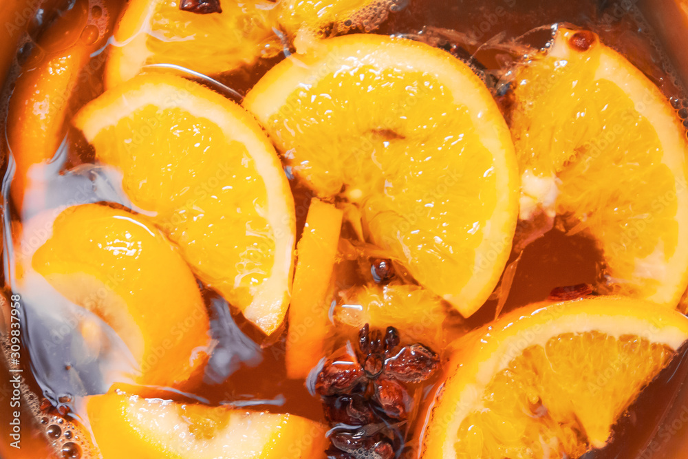 Making hot alcoholic mulled wine with oranges and spices. Christmas beverages boil in the metal pan. Glintwine from rose wine with citrus, cloves, star anise, cinnamon. Making hot alcoholic mulled wine with oranges and spices. Christmas beverages boil in the metal pan. Glintwine from rose wine with citrus, cloves, star anise, cinnamon.
