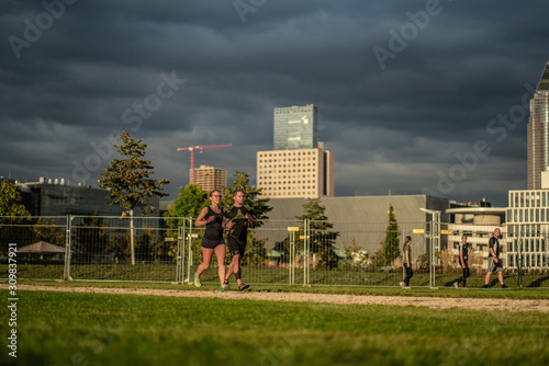 Two young attractive athletes run in the park of a modern city