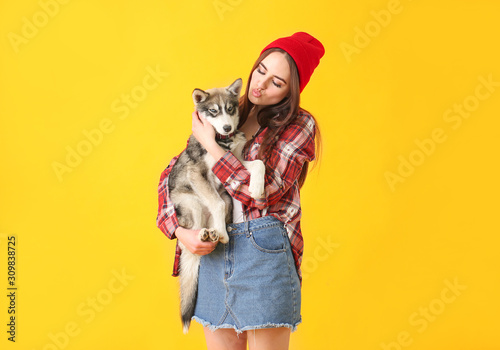 Stylish woman with funny husky puppy on color background