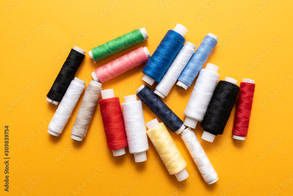 colored sewing threads on yellow background colored sewing threads on yellow background