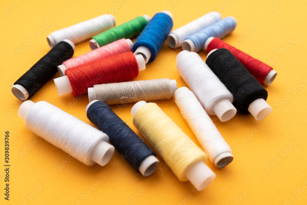 colored sewing threads on yellow background colored sewing threads on yellow background